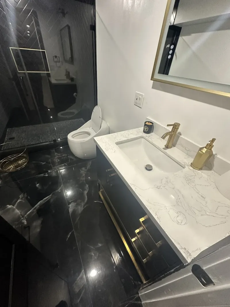 Hackensack, NJ bathroom remodel: dark vanity with gold hardware and a stone-look top