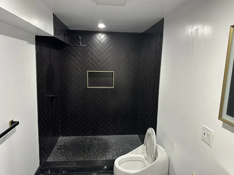 Hackensack, NJ bathroom remodel: after: black herringbone walk-in shower with a pebble floor