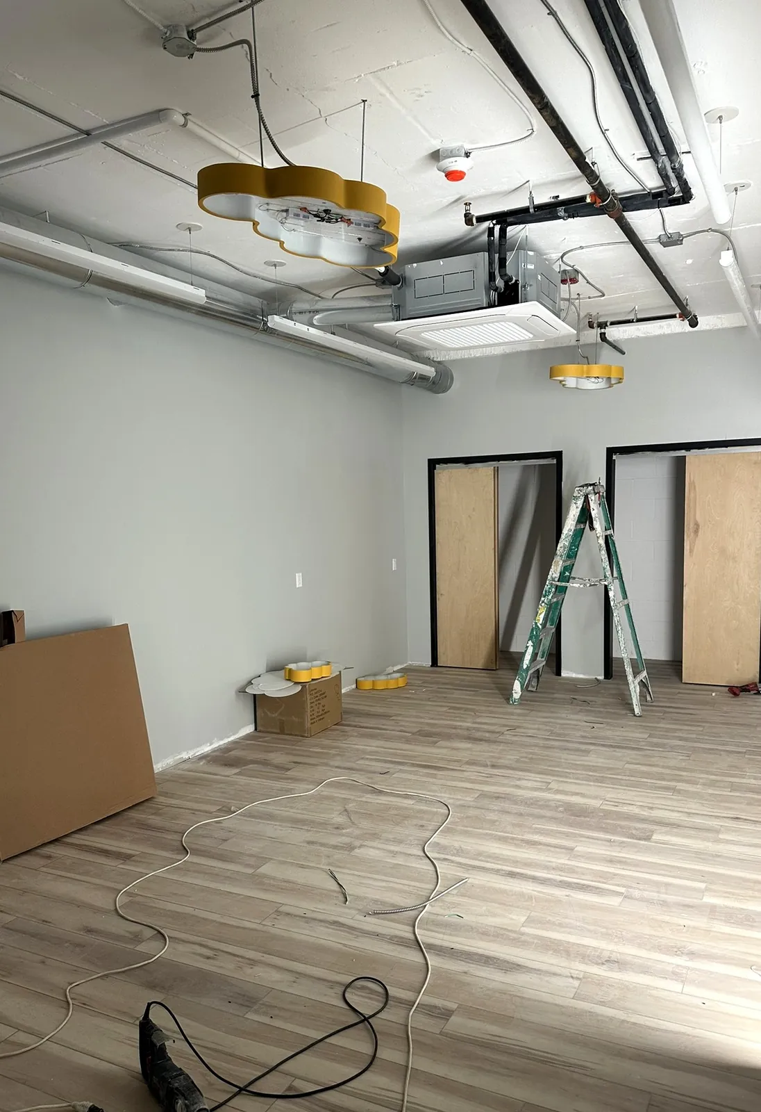 Painted room with new wood-look plank floor, ceiling cassette unit and new light fixtures going in