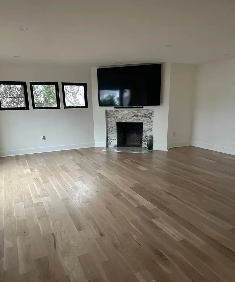Hackensack, NJ living room renovation: after: wide-plank hardwood and a refaced stone fireplace