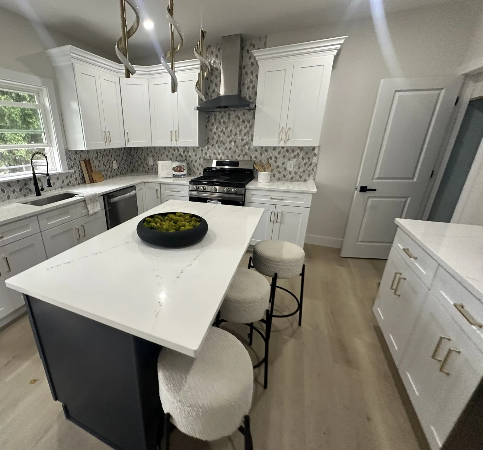 Finished kitchen with white shaker cabinets, gold pulls, mosaic backsplash and stainless range