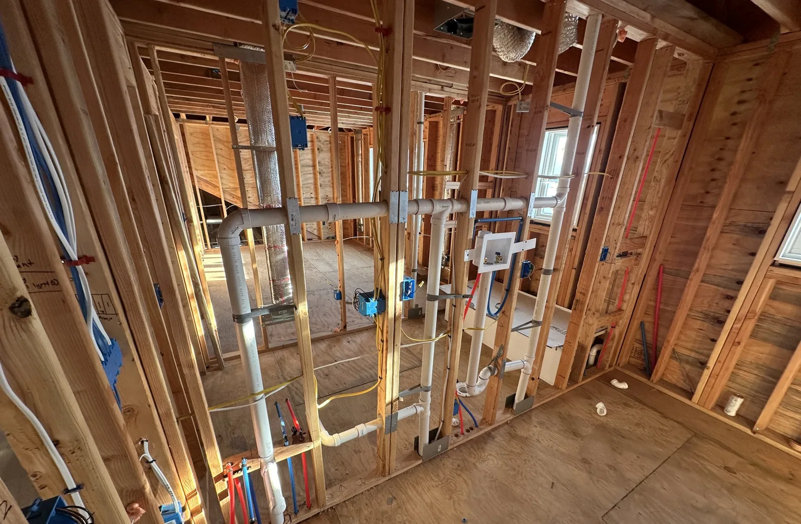 Open stud walls with new drain and vent piping, water lines and electrical boxes before insulation