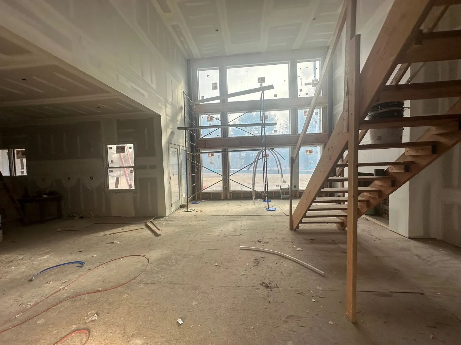 Same two-story room after drywall, with tall windows and open staircase
