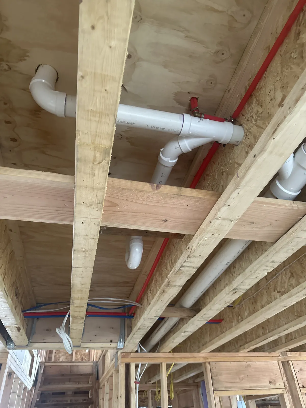 New PVC drain and vent piping roughed in through open wall and floor framing