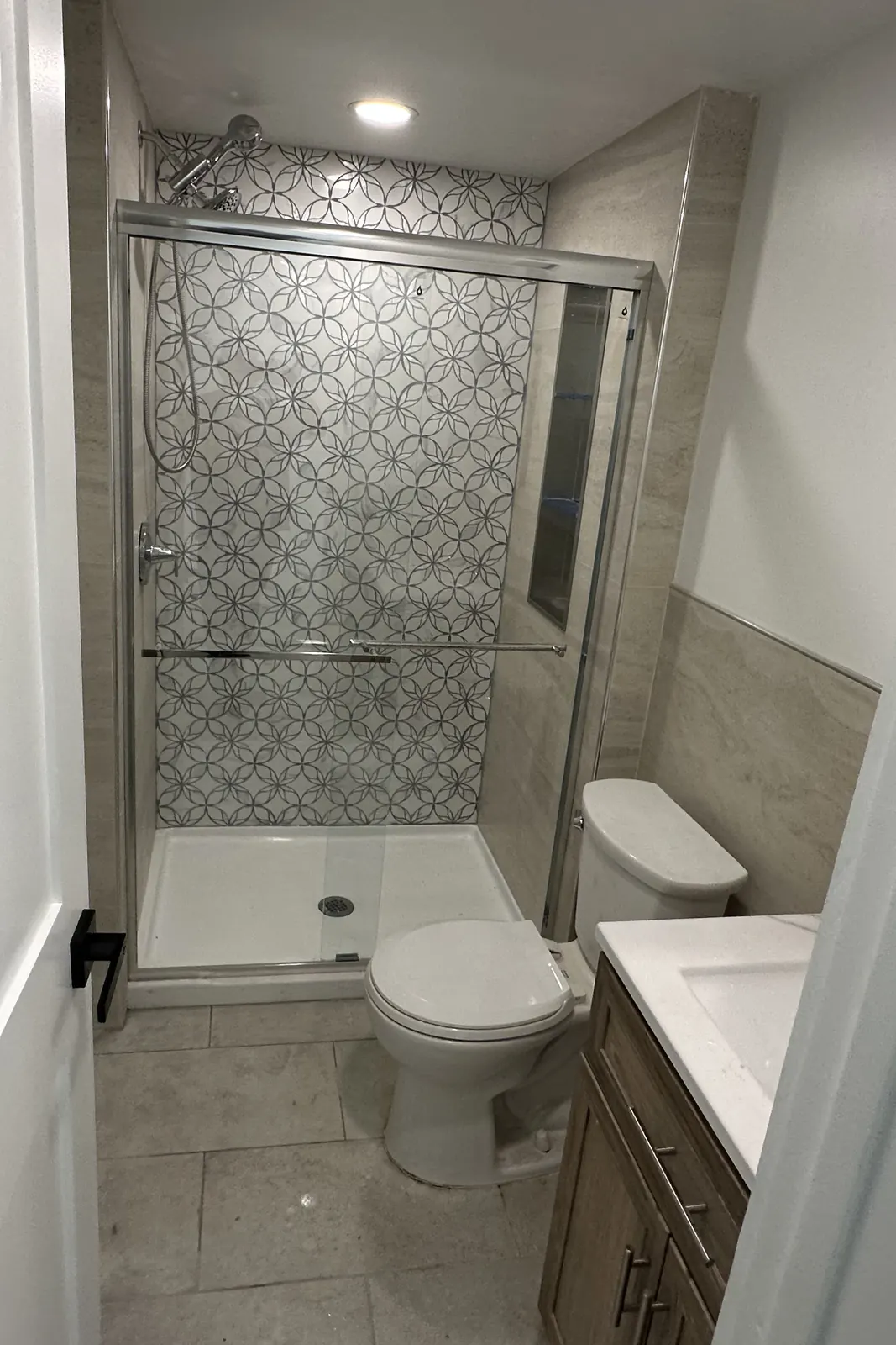 New full bathroom with a tiled shower and glass slider built inside a detached garage