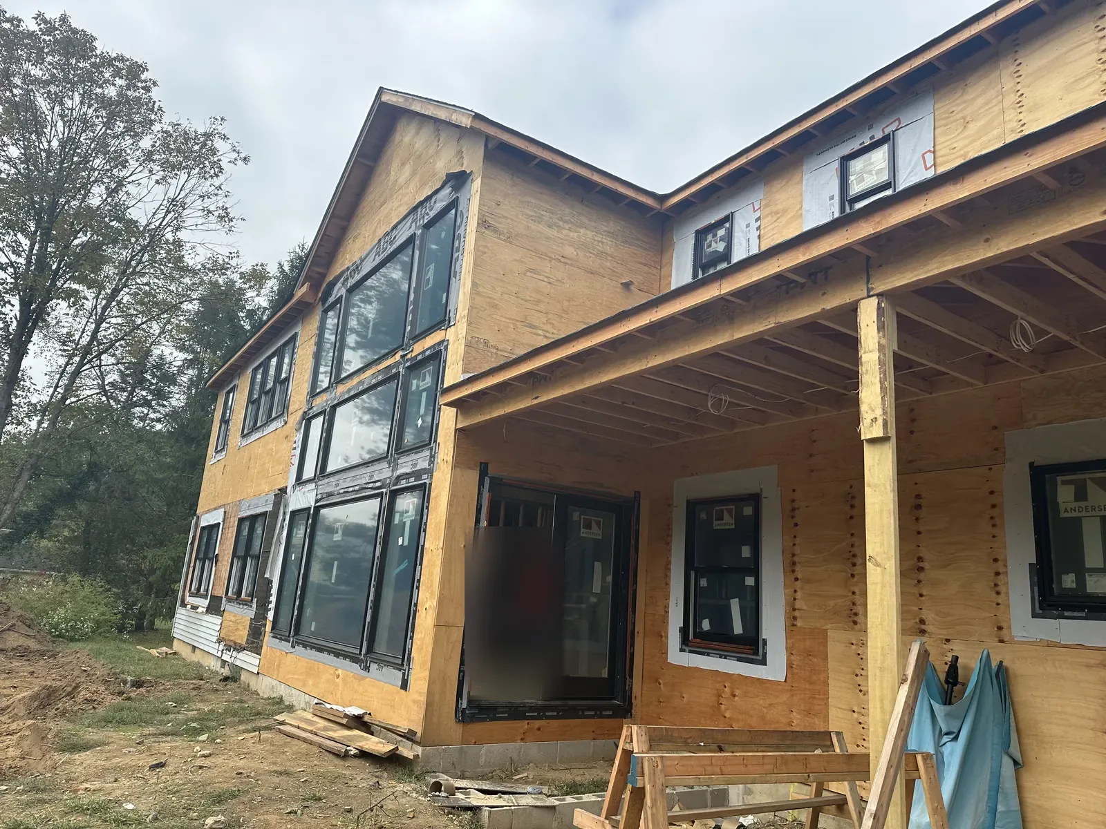 New construction house with sheathing, black-framed windows and a covered porch