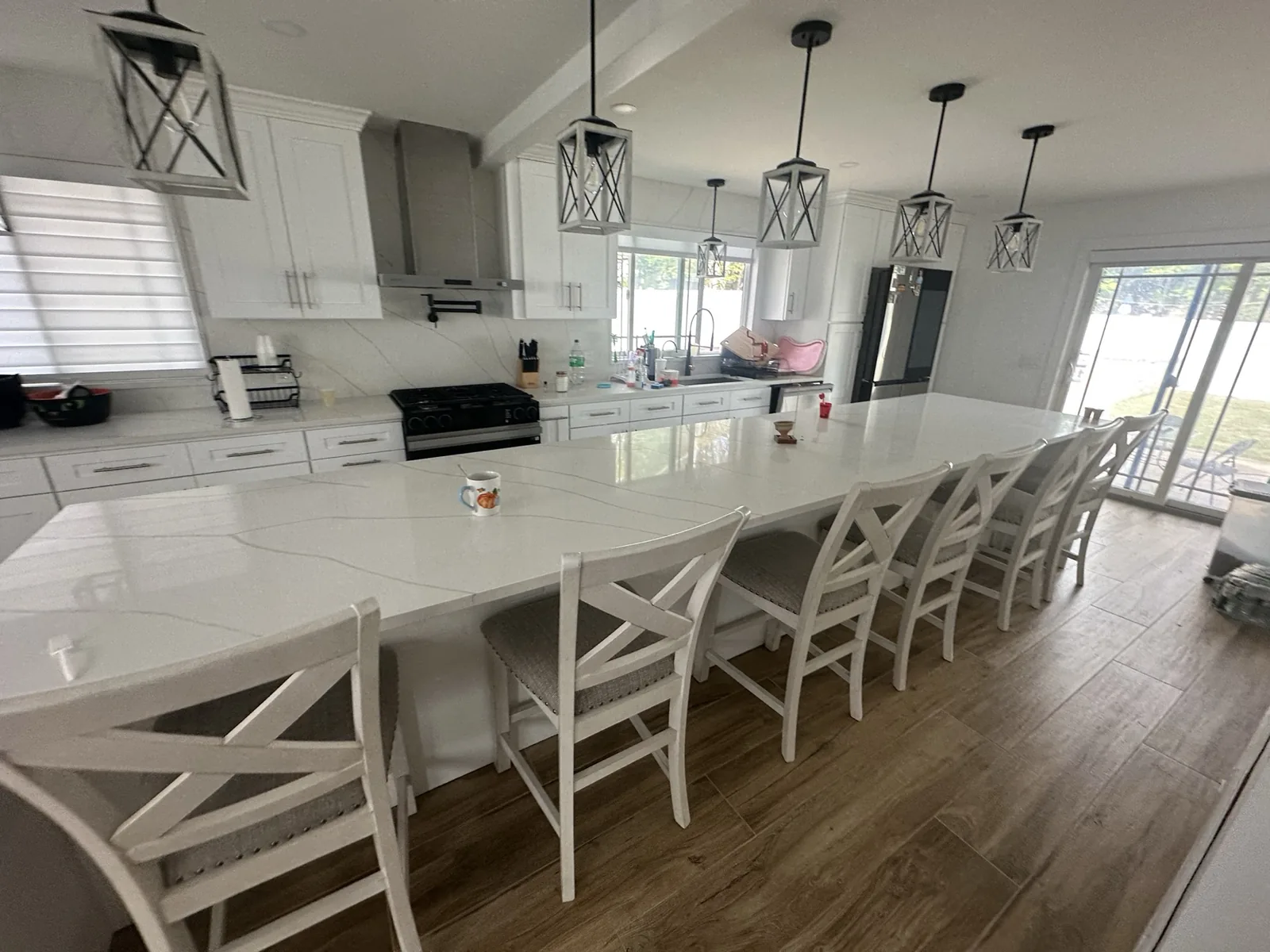 Open-plan kitchen with a full-length island, lantern pendants and white shaker cabinetry
