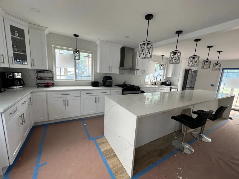 Finished kitchen remodel in Lake Hiawatha, NJ with white shaker cabinets, a waterfall quartz island and black pendant lights