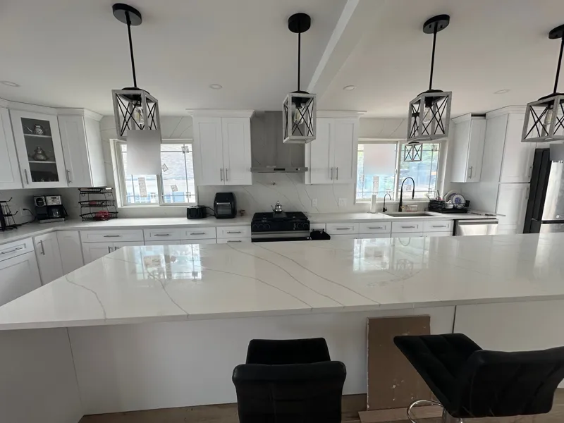 Front view of a quartz kitchen island with bar stools and pendant lights in a Parsippany, NJ kitchen remodel